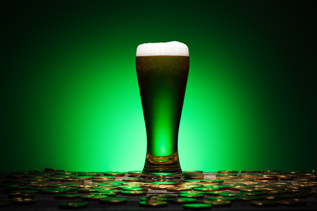 Sklenka Irské pivo stojí na dřevěný stůl na zeleném pozadí - Fotografie, Obrázek