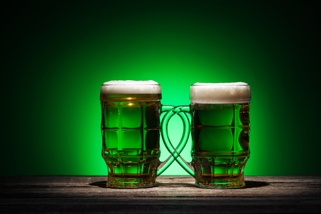 copos de cerveja irlandesa em pé sobre mesa de madeira no fundo verde
 - Foto, Imagem