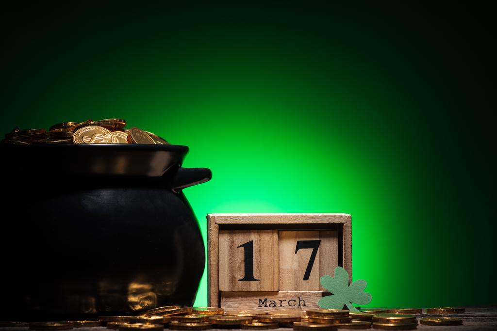 cube calendar with date near golden coins in pot on green background - Photo, Image