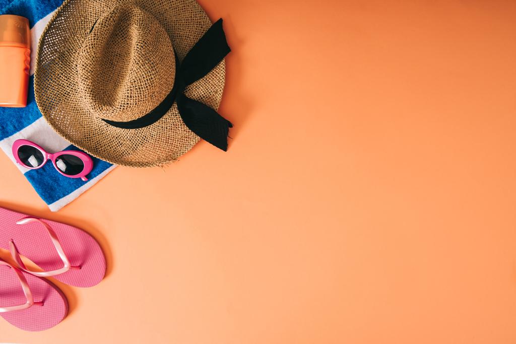 bovenaanzicht van zomer accessoires en zonnebrandcrème op oranje achtergrond - Foto, afbeelding
