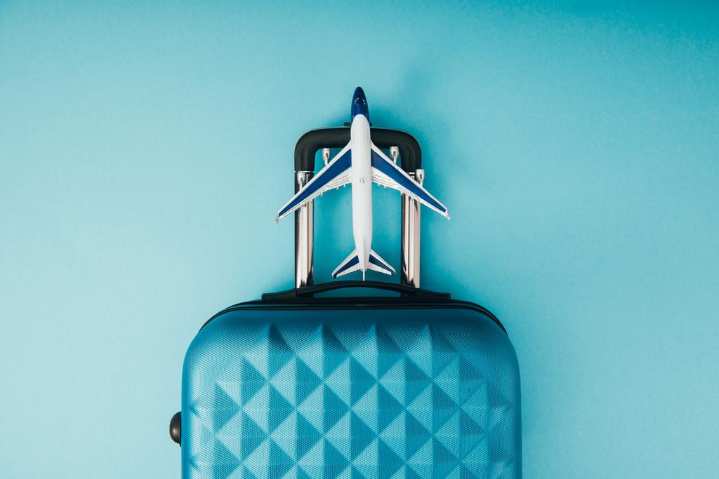 pohled modelu letadla shora a cestovní taška na modrém pozadí - Fotografie, Obrázek