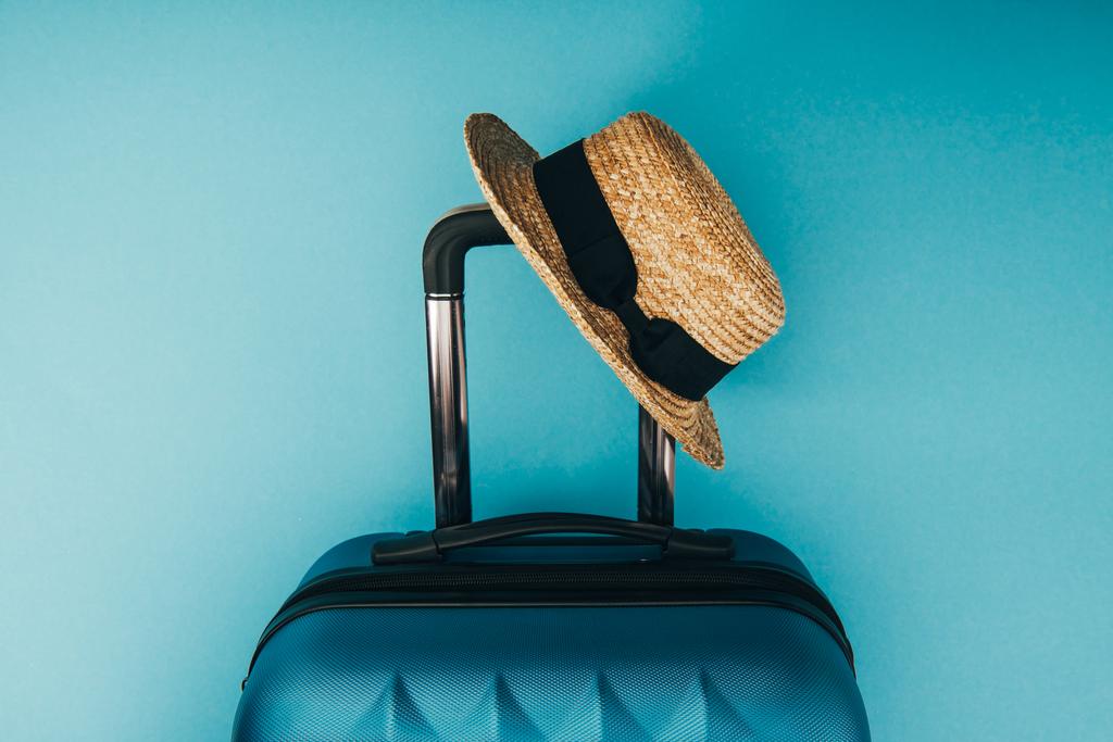 top view of straw hat and travel bag on blue background - Photo, Image