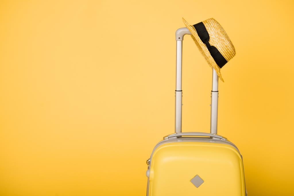 zářivě žluté cestovní tašku a sláma klobouk na žlutém podkladu - Fotografie, Obrázek