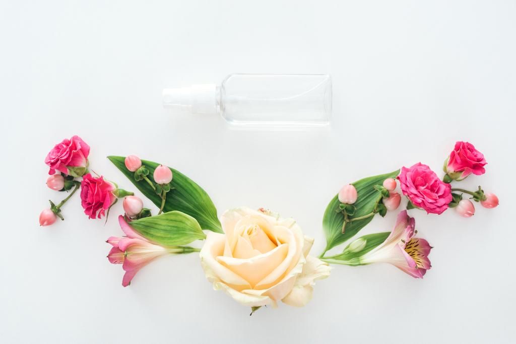 vista superior de la composición con alstroemeria, rosas, bayas y botella de spray vacía sobre fondo blanco
 - Foto, imagen