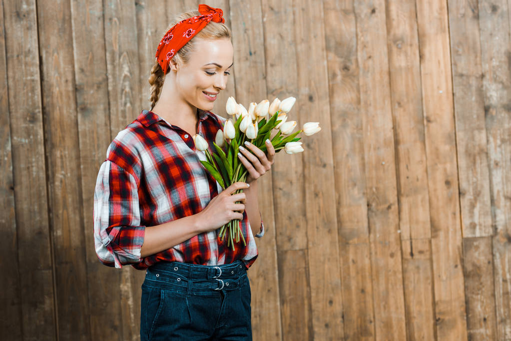 fröhliche Frau lächelt beim Anblick von Tulpen  - Foto, Bild