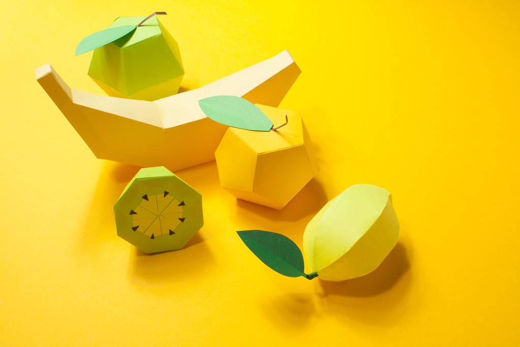 Fruta hecha de papel. Fondo amarillo. Hay espacio para escribir. Trópicos. Acostado. Manzana, limón, plátano y kiwi. Concepto amarillo de verano
 - Foto, imagen