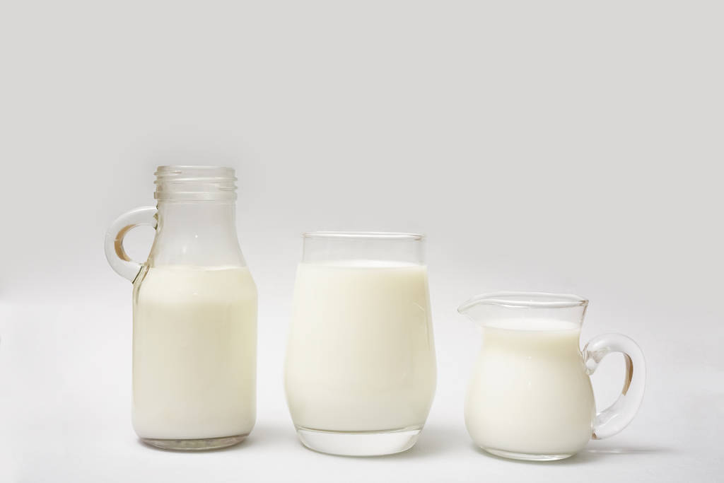 Butelka mleka, dzbanek i szklankę mleka na białym tle na tle papieru - Zdjęcie, obraz