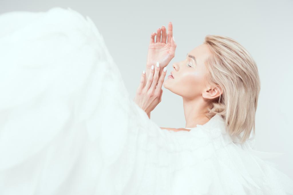 enfoque selectivo de hermosa mujer tierna con alas de ángel gesto con las manos aisladas en blanco
 - Foto, imagen