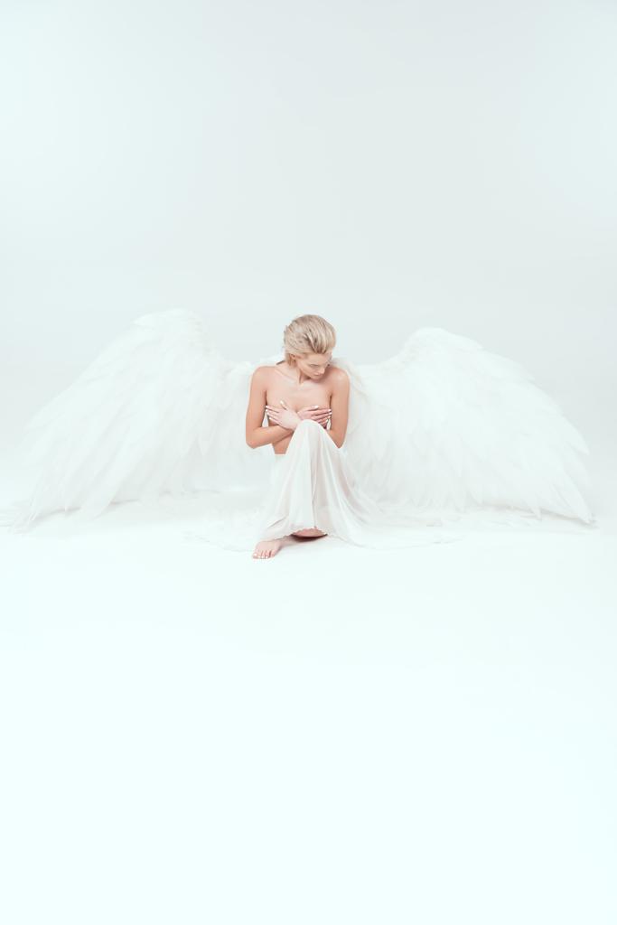 beautiful woman with angel wings sitting and posing isolated on white with copy space - Photo, Image