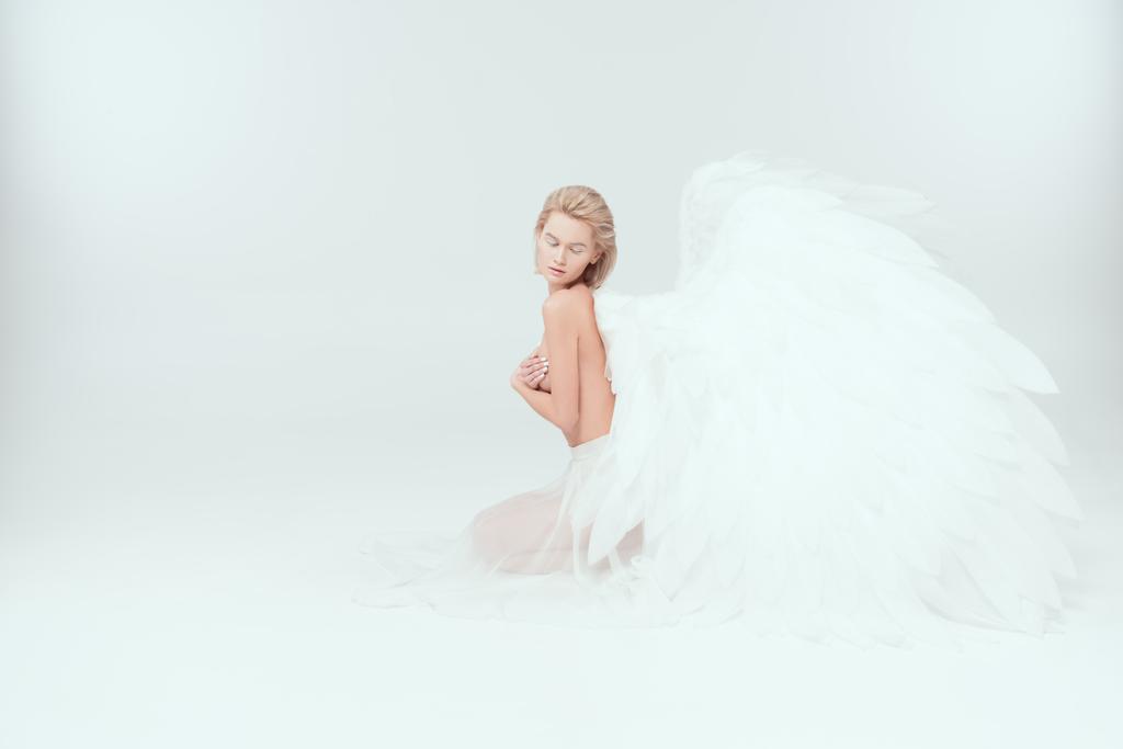 gyönyörű nő angyal szárnyak ülő és jelentő elszigetelt fehér másol hely - Fotó, kép