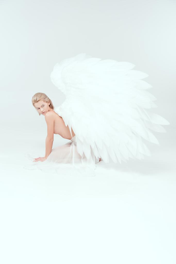 beautiful half naked young woman with angel wings posing on white background - Photo, Image