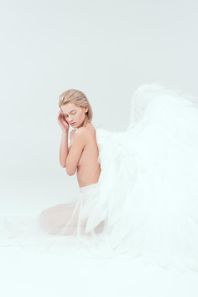 hermosa mujer con alas de ángel sentado con los ojos cerrados aislado en blanco
 - Foto, Imagen