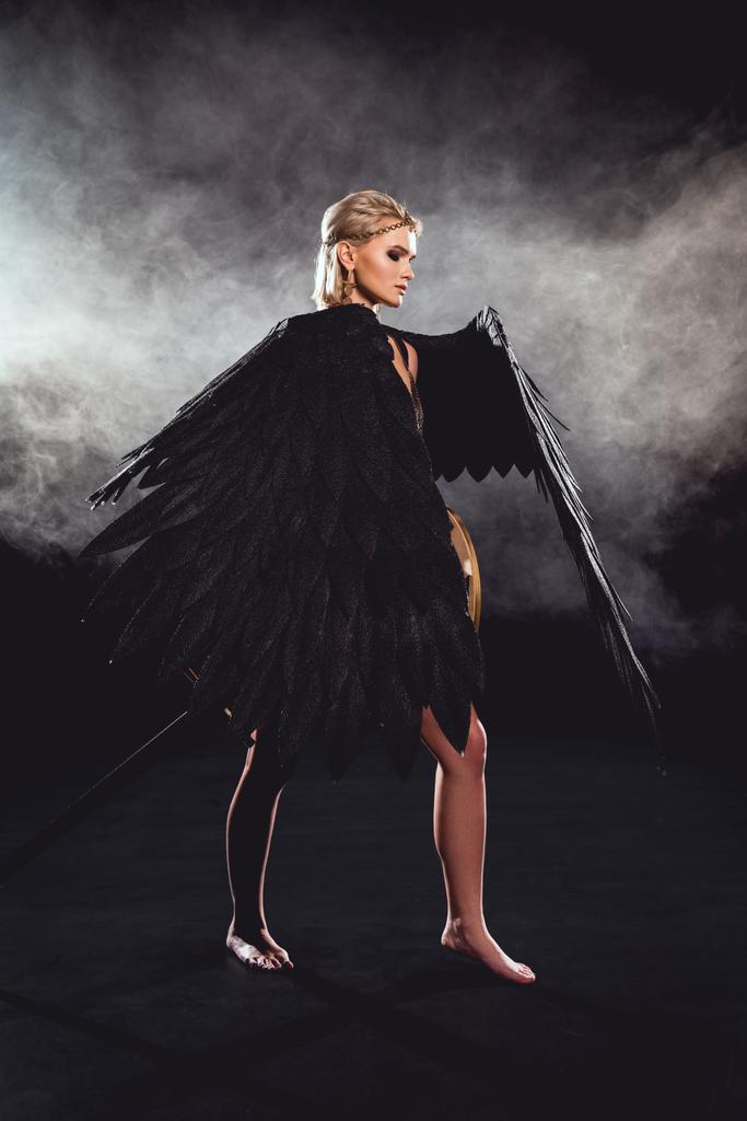 piękna kobieta, czarny Anioł skrzydła i mieczem pozowanie na czarnym tle - Zdjęcie, obraz