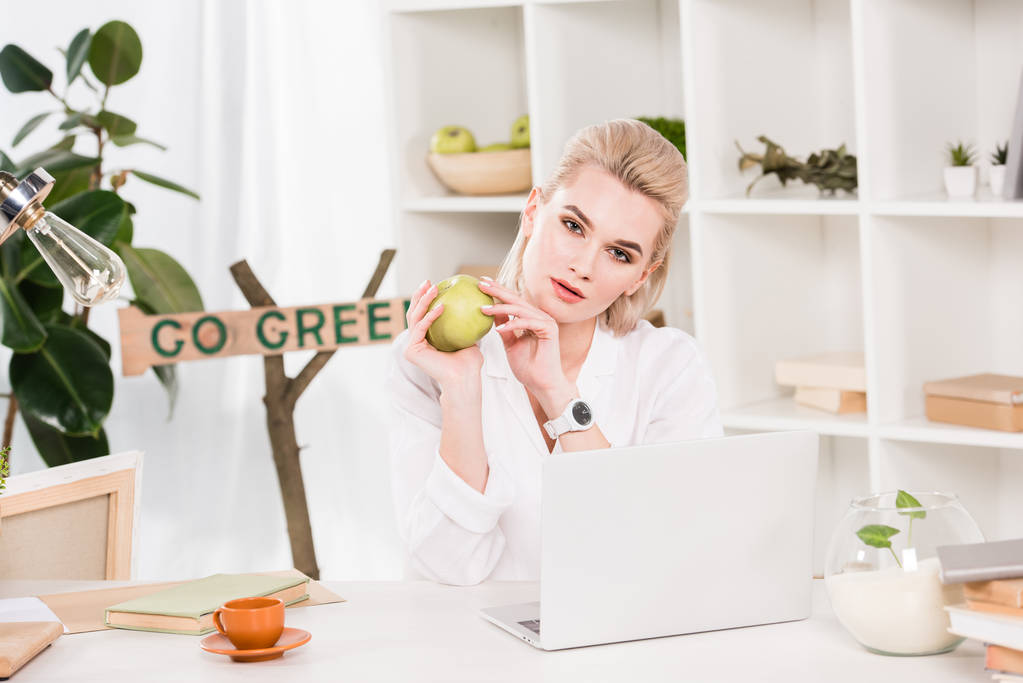 houkutteleva nainen tilalla vihreä omena ja istuu lähellä mennä vihreä merkki, ympäristön säästäminen käsite
  - Valokuva, kuva