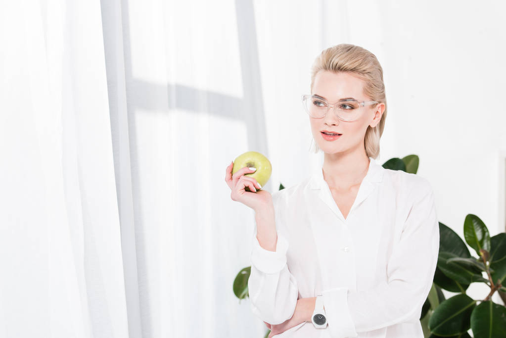 femme d'affaires heureuse dans des lunettes tenant pomme verte au bureau
  - Photo, image