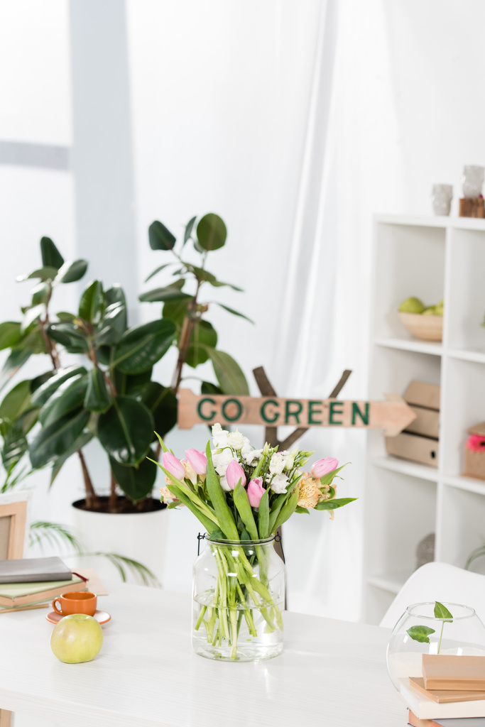 selective focus of flowers in glass vase near wooden sign with go green lettering on background, environmental saving concept  - Photo, Image