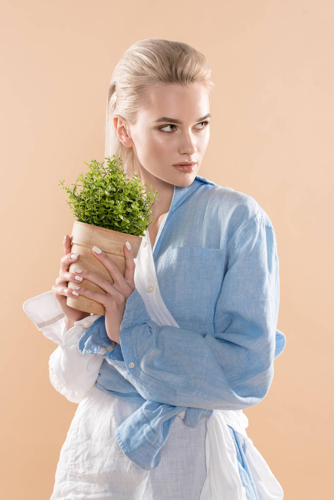 žena držící Květináč s rostlinou a stojící v eco oblečení izolované na béžové, ekologické ukládání konceptu  - Fotografie, Obrázek