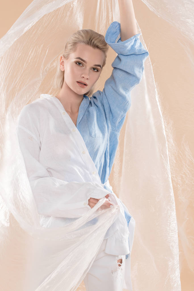 žena držící polyethylenu stoje v eco oblečení izolované na béžové, ekologické ukládání konceptu  - Fotografie, Obrázek