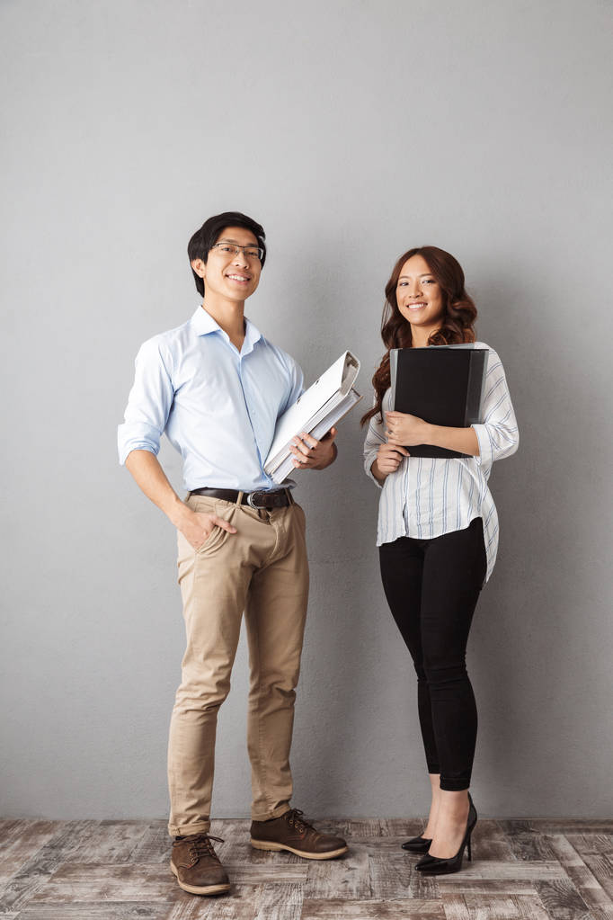 piena lunghezza di un felice asiatico business coppia di lavoro insieme con documenti su sfondo grigio
 - Foto, immagini
