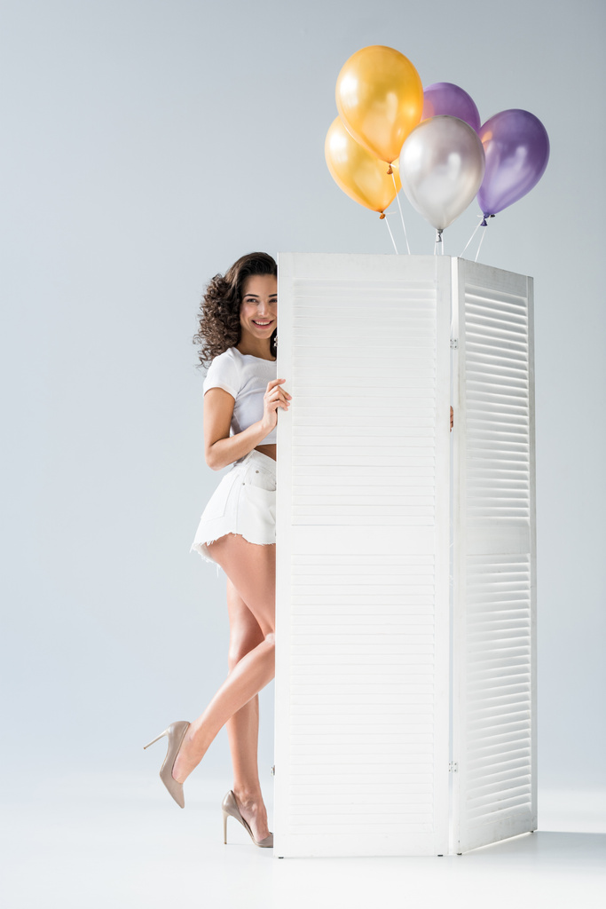 Elegante ragazza riccia con palloncini d'aria in posa su sfondo grigio
 - Foto, immagini