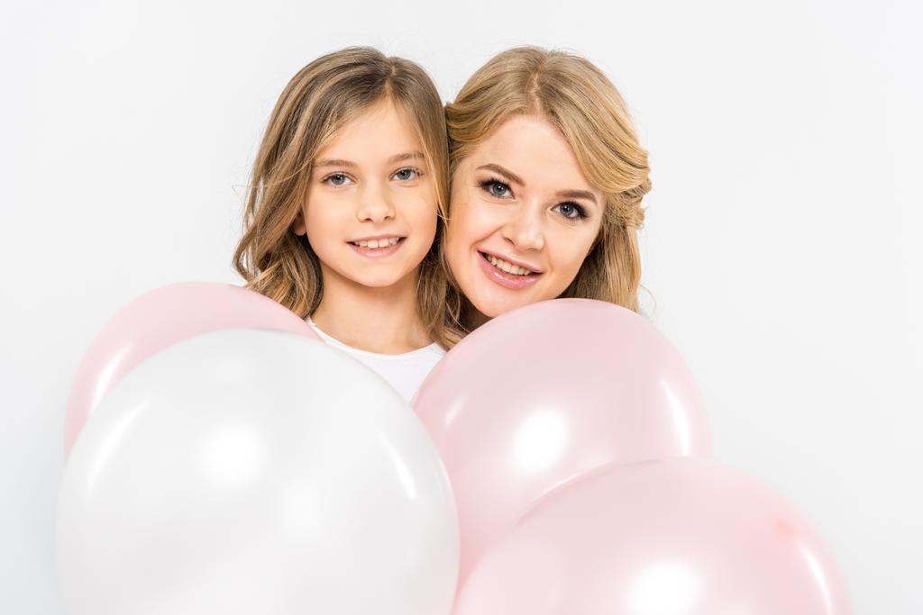 mosolyog, anya és lánya, fehér és rózsaszín hőlégballonok, fehér háttér mögé bújva - Fotó, kép