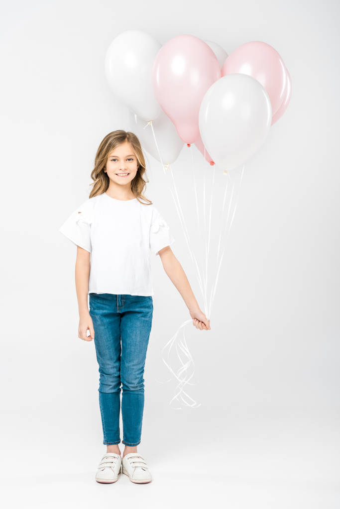 roztomilé dítě v bílé tričko a modré džíny drží slavnostní balónů na bílém pozadí - Fotografie, Obrázek