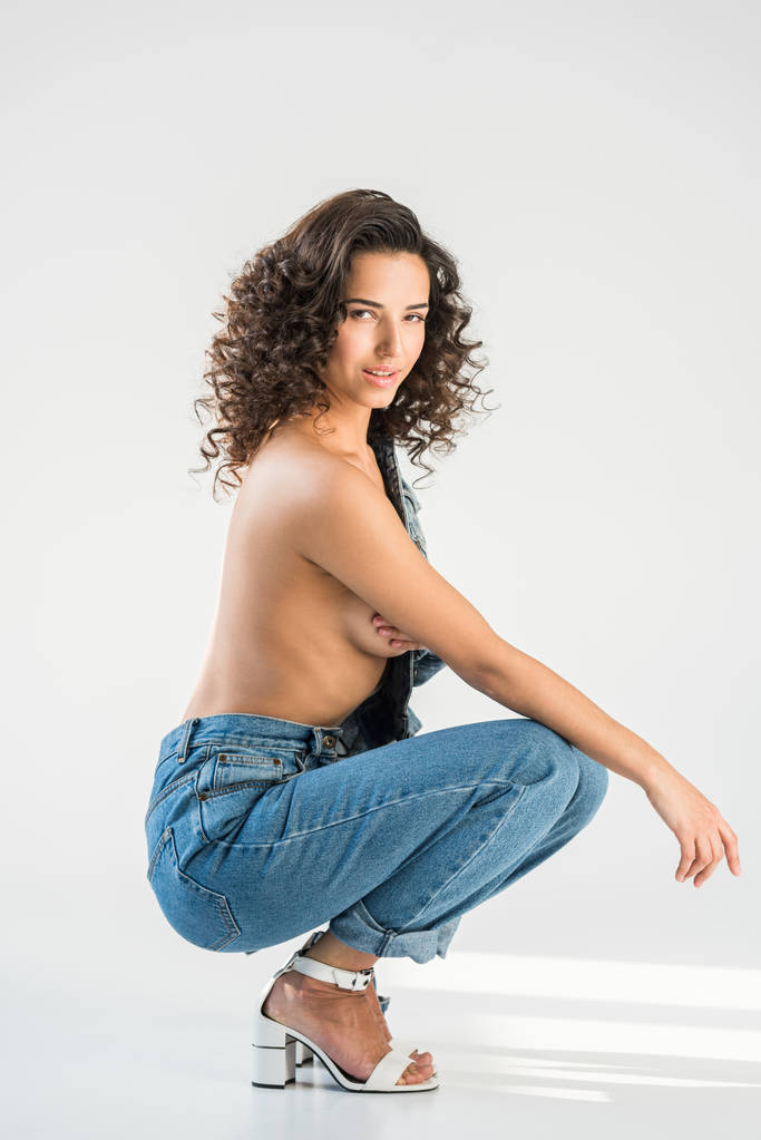 Chica topless rizado en jeans sentado sobre fondo gris
 - Foto, imagen