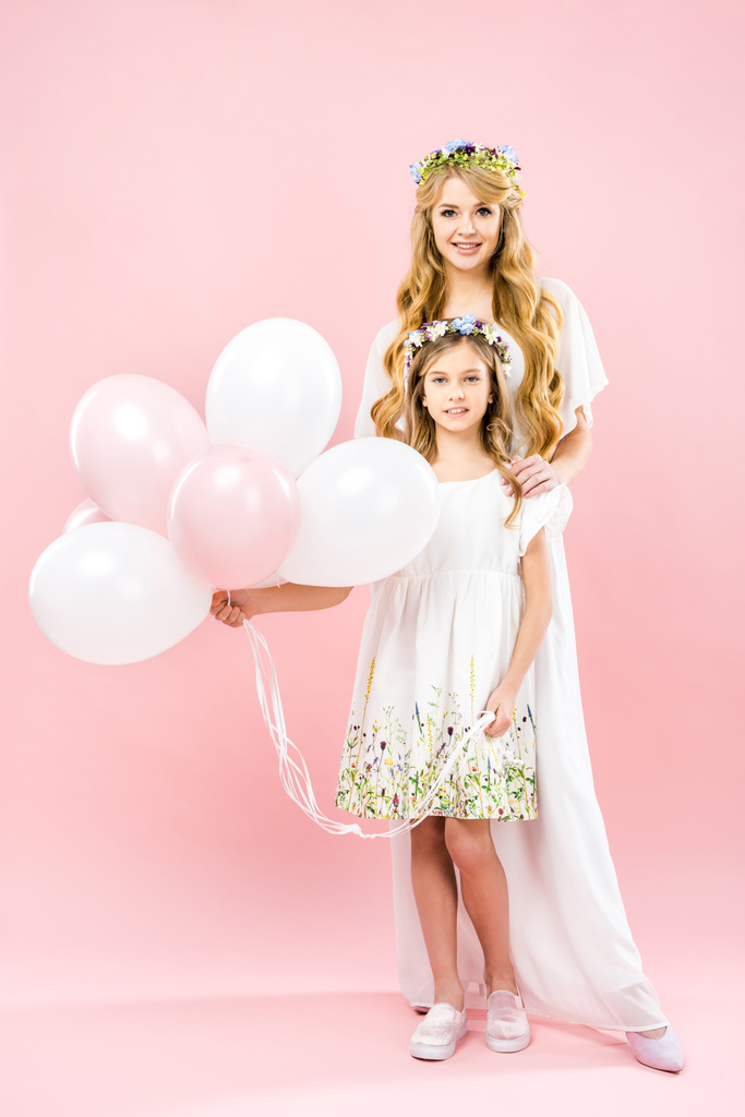 entzückende Tochter hält festliche Luftballons in der Nähe der schönen Mutter auf rosa Hintergrund - Foto, Bild
