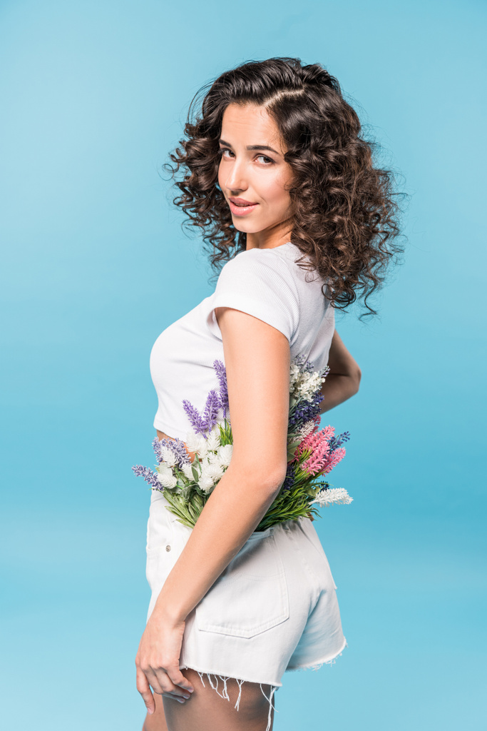 Aantrekkelijke curly girl bloemboeket houden op blauwe achtergrond - Foto, afbeelding
