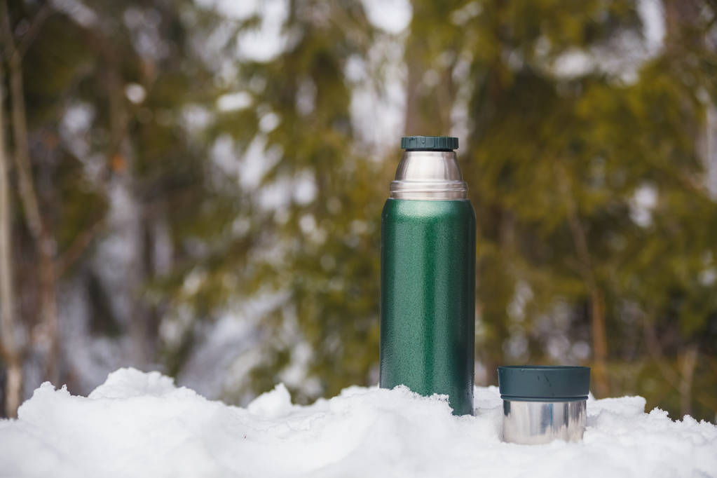 Chá de uma garrafa térmica na floresta de inverno
 - Foto, Imagem