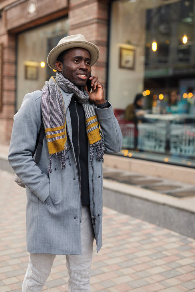 Homem americano africano feliz fala com seu amigo por smartphone andando na cidade
 - Foto, Imagem