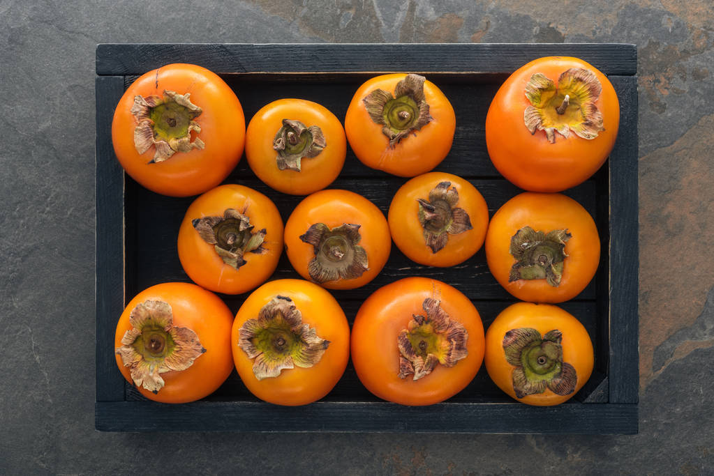 top view of orange and whole persimmons in wooden box  - Photo, Image
