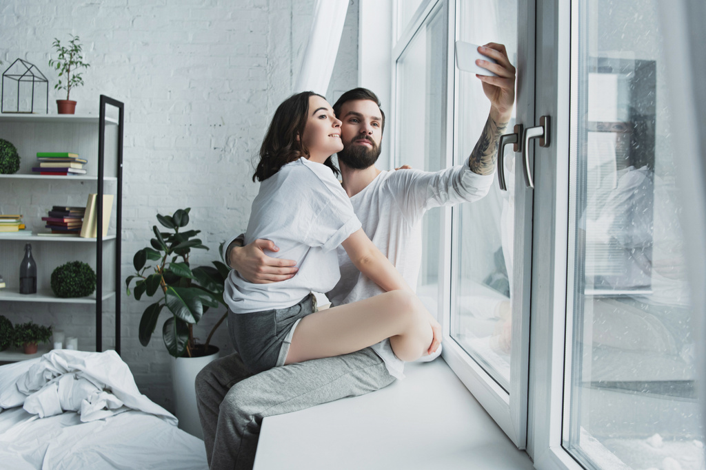 beautiful young couple taking selfie on smartphone at home - Photo, Image