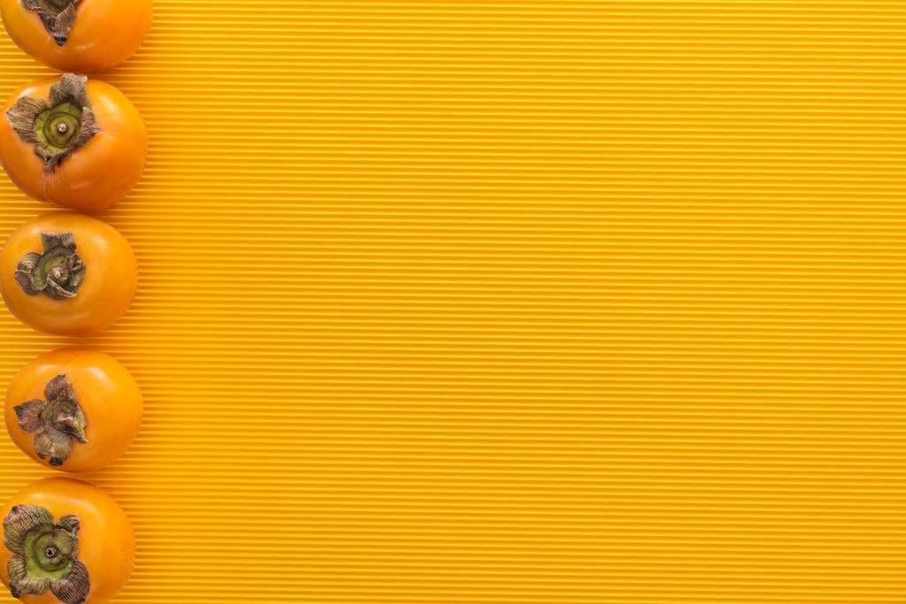 vista superior de caquis naranjas sobre fondo amarillo con espacio para copiar
 - Foto, imagen