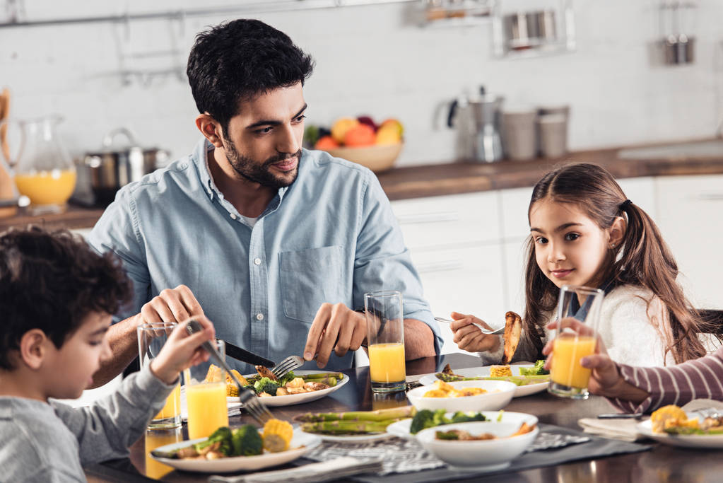 bonito latina pai olhando para filha enquanto tendo almoço perto de filho e mulher
 - Foto, Imagem