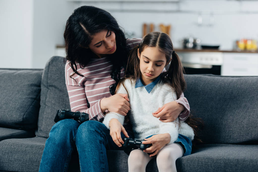 matka Łacińskiej przytulanie zdenerwowany córka po gry wideo w domu - Zdjęcie, obraz