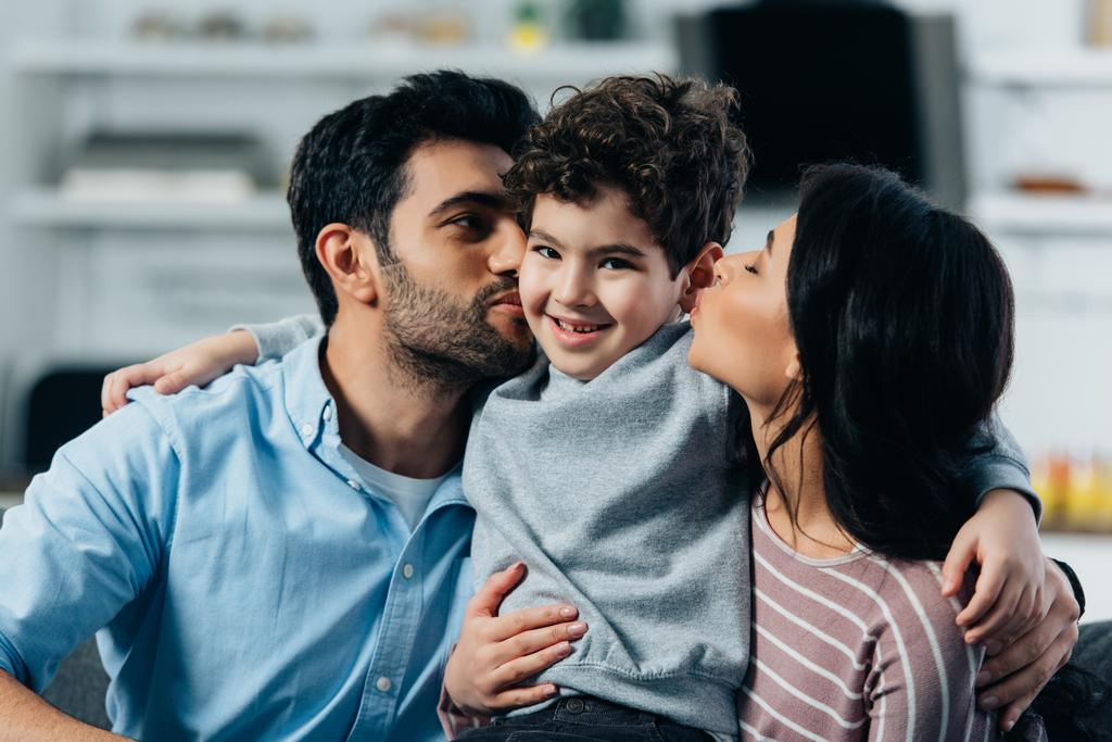 ευτυχισμένος Λατινική πατέρα και μητέρα φιλιά τα μάγουλα του χαριτωμένο γιου στο σπίτι - Φωτογραφία, εικόνα