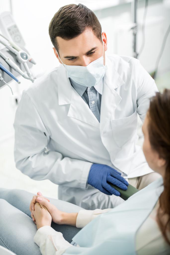 селективная направленность стоматолога в маске на женщину в стоматологической клинике
 - Фото, изображение