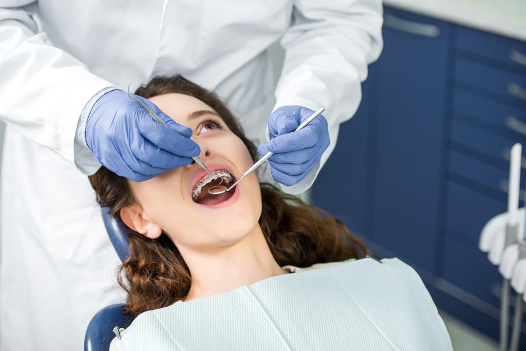 weergave van de examencommissie vrouw tandarts in bretels met geopende mond bijgesneden  - Foto, afbeelding