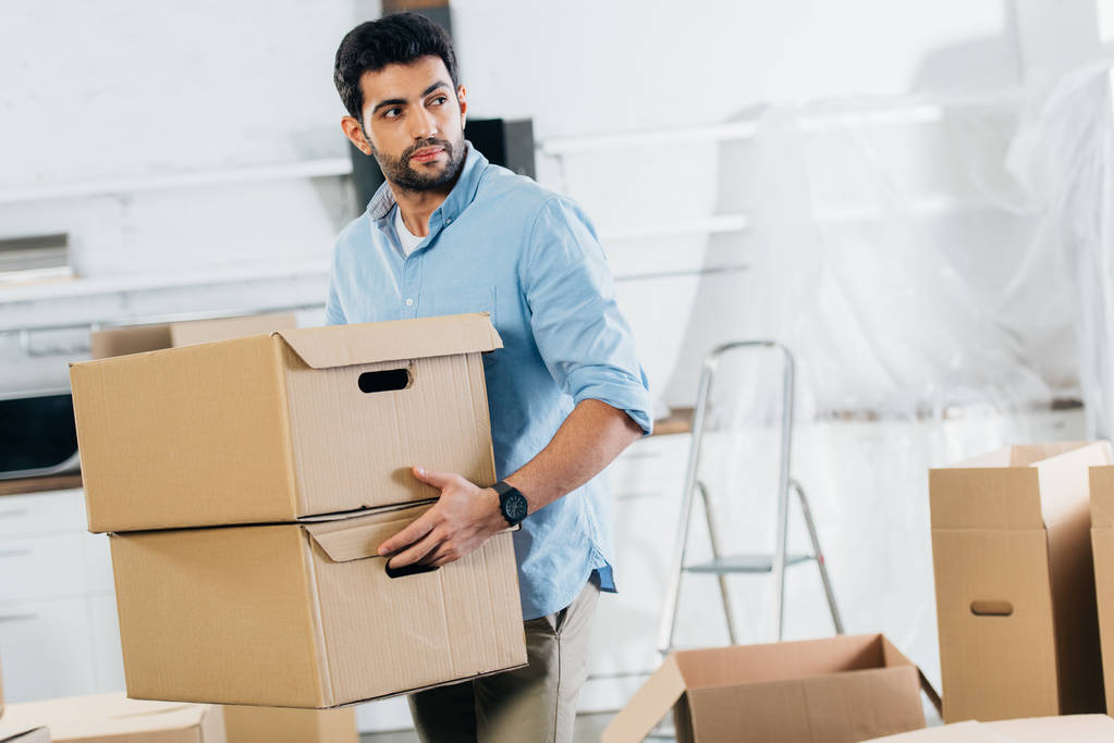 bonito latina homem segurando caixas enquanto se movendo no novo lar
  - Foto, Imagem