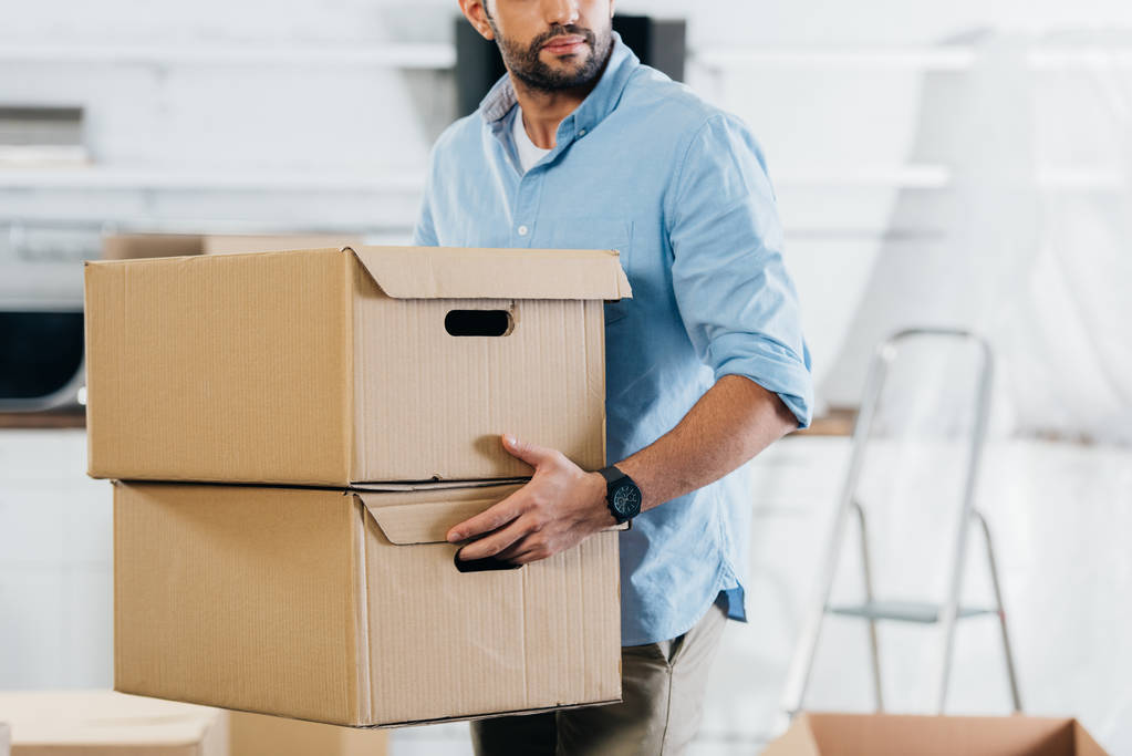 vista recortada del hombre sosteniendo cajas mientras se mueve en un nuevo hogar
  - Foto, Imagen