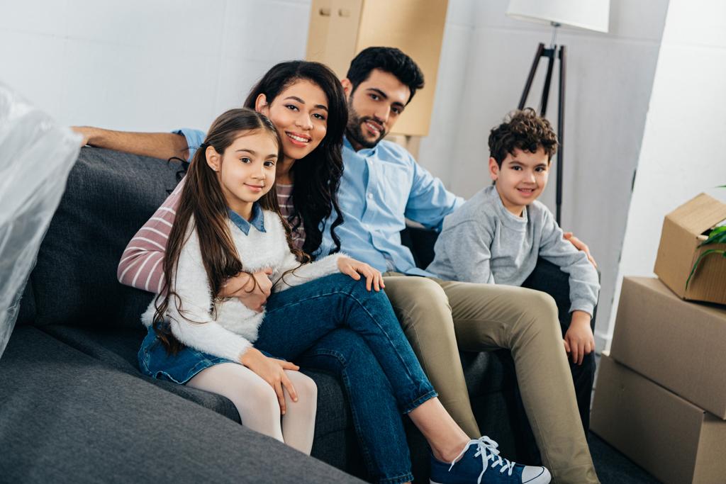 счастливая латиноамериканская семья сидит на диване в новом доме
 - Фото, изображение
