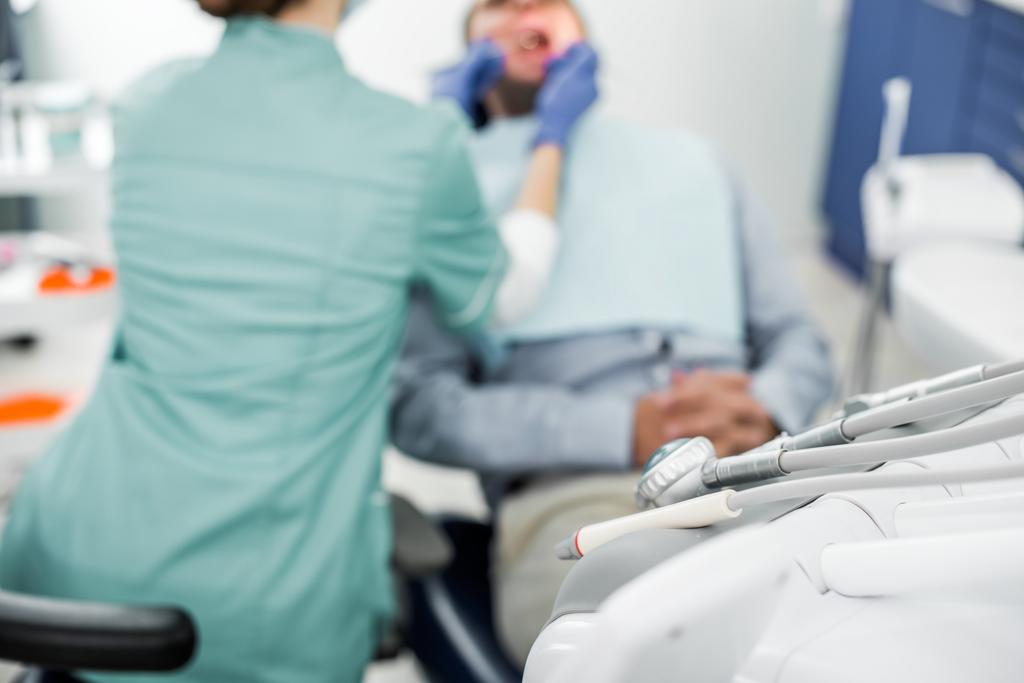 selective focus of dental instruments with dentist examining patient on background - Photo, Image