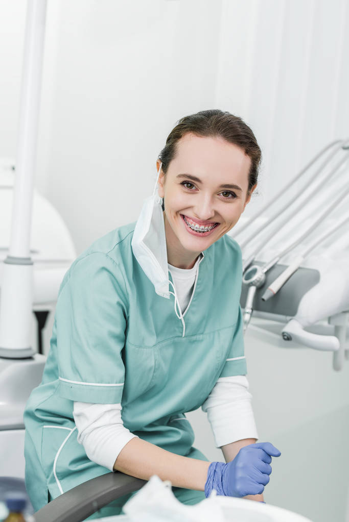schöne Zahnärztin mit Zahnspange auf Zähnen lächelnd in Zahnklinik - Foto, Bild