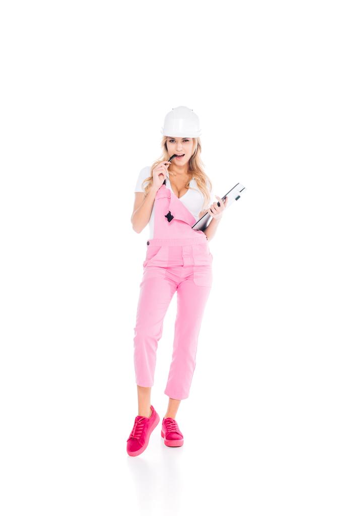 ピンクのオーバー オール、白い背景の上に紙クリップボード ペンとヘルメットの便利な女 - 写真・画像