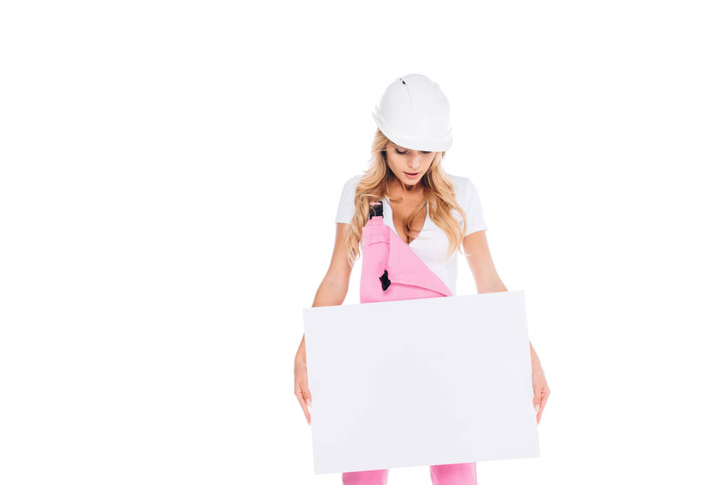 blonde femme pratique en uniforme rose, casque de sécurité tenant la plaque isolée sur blanc
 - Photo, image