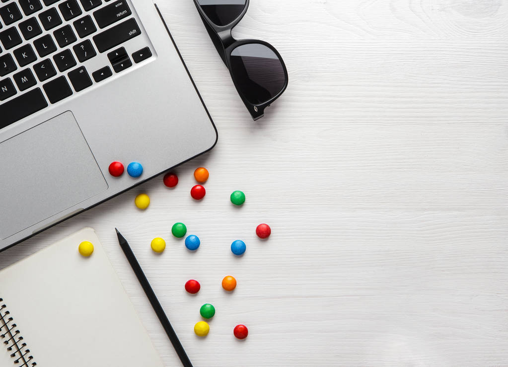 portátil, portátil con un lápiz y caramelos de colores sobre un fondo de madera blanca. Copyspace plano de la disposición
. - Foto, imagen