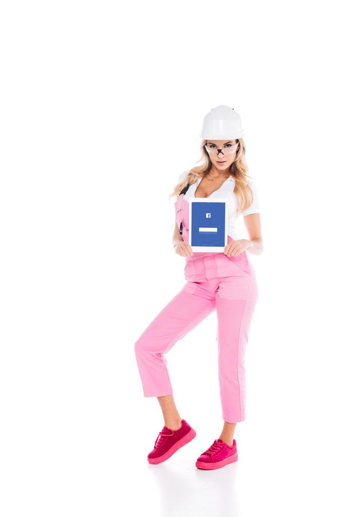 白い背景の画面で facebook アプリでデジタル タブレットを保持しているピンクの制服を着た魅力的な便利な女性 - 写真・画像