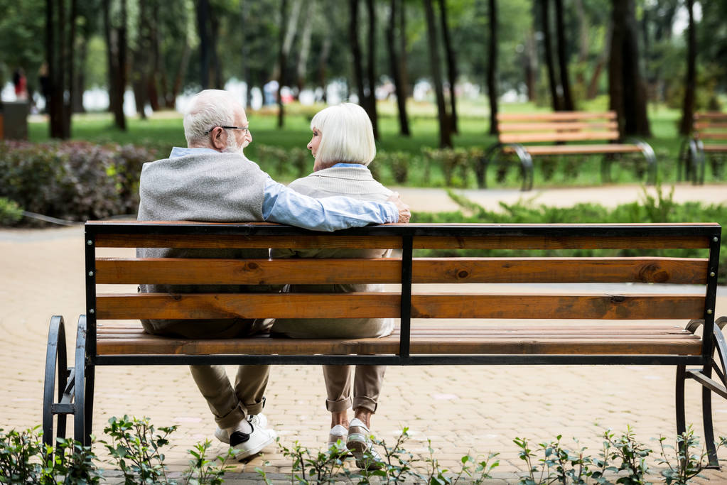 vanhempi pari istuu puinen penkki puistossa
 - Valokuva, kuva