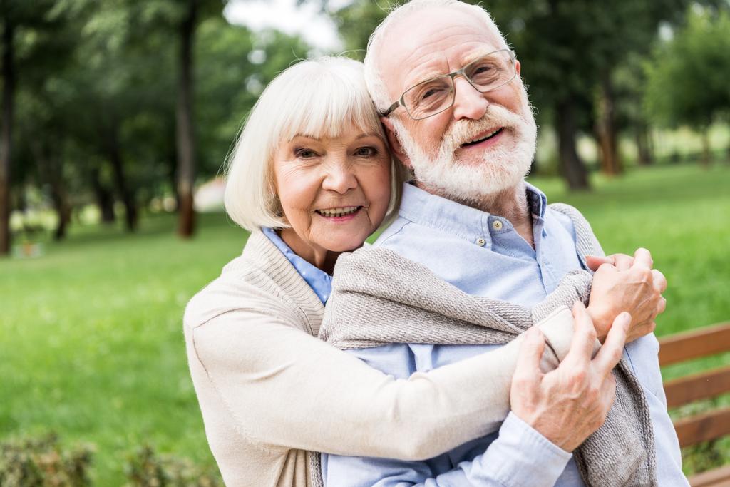 feliz anciana abrazando sonriente marido en parque
 - Foto, imagen